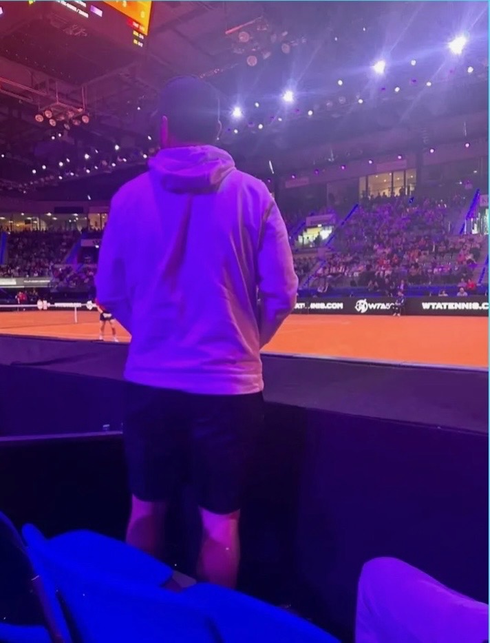Adam standing courtside at a professional tennis match